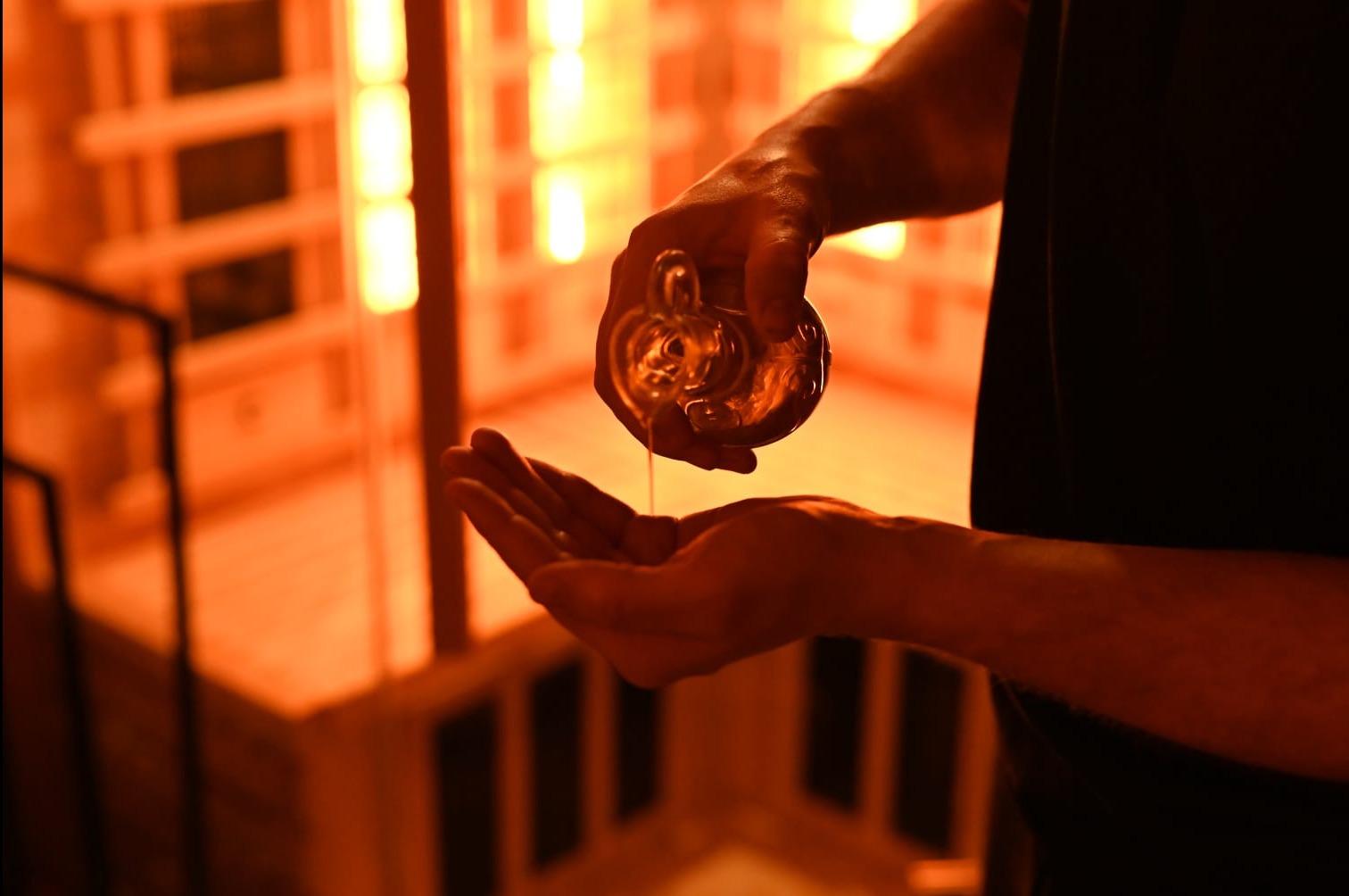 Olejkowy płyn wylewany z ozdobnej butelki na dłonie w saunie infrared w Krakowie.