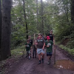 LASOMIR - Grupa dzieci z kijkami w lesie, idąca po błotnistej drodze. Uczestnicy leśnej wyprawy edukacyjnej, zorganizowanej przez agencję eventową. Aktywny wypoczynek na łonie natury.