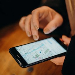 BGU Usługi Transportowe Przeprowadzki Transport Mebli Białystok - Osoba przegląda mapę na smartfonie, prawdopodobnie planując trasę, z widocznym niebieskim znacznikiem lokalizacji.