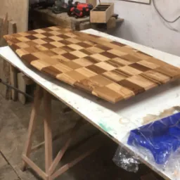 Blat drewniany w szachownicę, wykonany z różnych odcieni drewna, na warsztacie w Wadowicach, widoczne narzędzia i akcesoria.