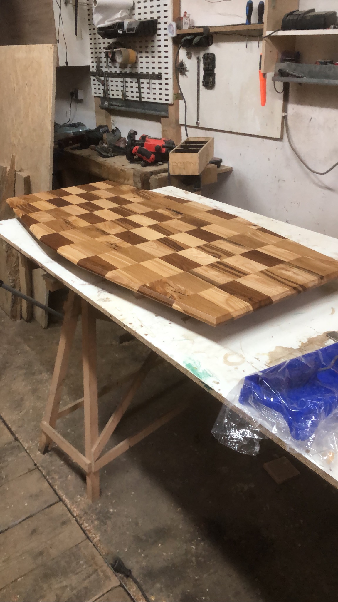 Blat drewniany w szachownicę, wykonany z różnych odcieni drewna, na warsztacie w Wadowicach, widoczne narzędzia i akcesoria.