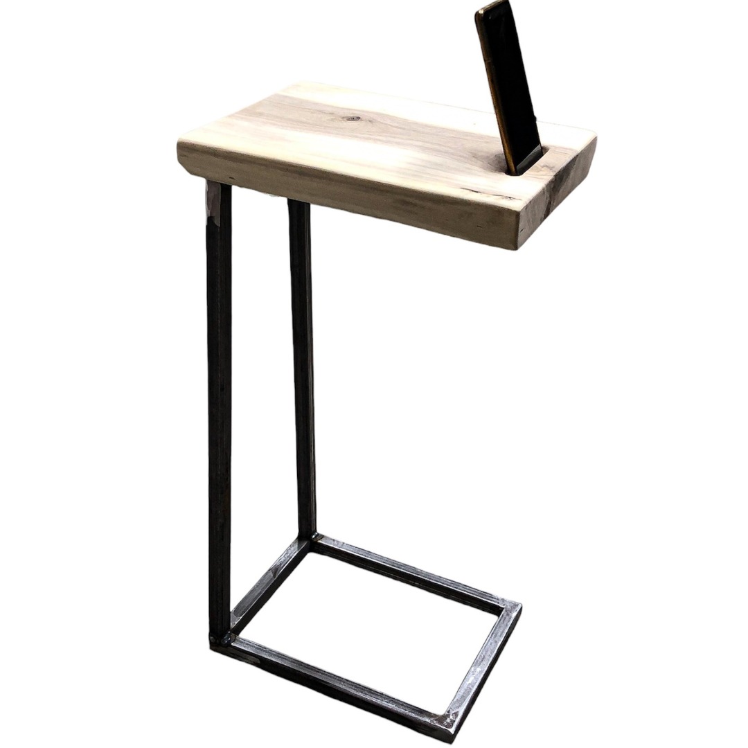 Stolik pomocniczy z blatem z jasnego drewna z widocznym usłojeniem i metalową ramą w kształcie litery C, z wbudowanym uchwytem na telefon.