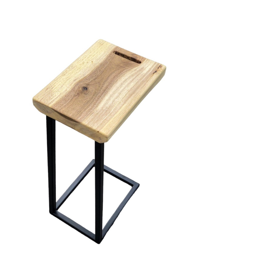 Stolik pomocniczy z blatem z litego drewna z widocznym usłojeniem i otworem na uchwyt, osadzony na czarnej, metalowej konstrukcji w kształcie litery U.