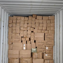 Relentless sp. z o.o. - Wnętrze kontenera wypełnione kartonami różnej wielkości, niektóre owinięte folią, z widocznymi etykietami i napisami Made in China.
