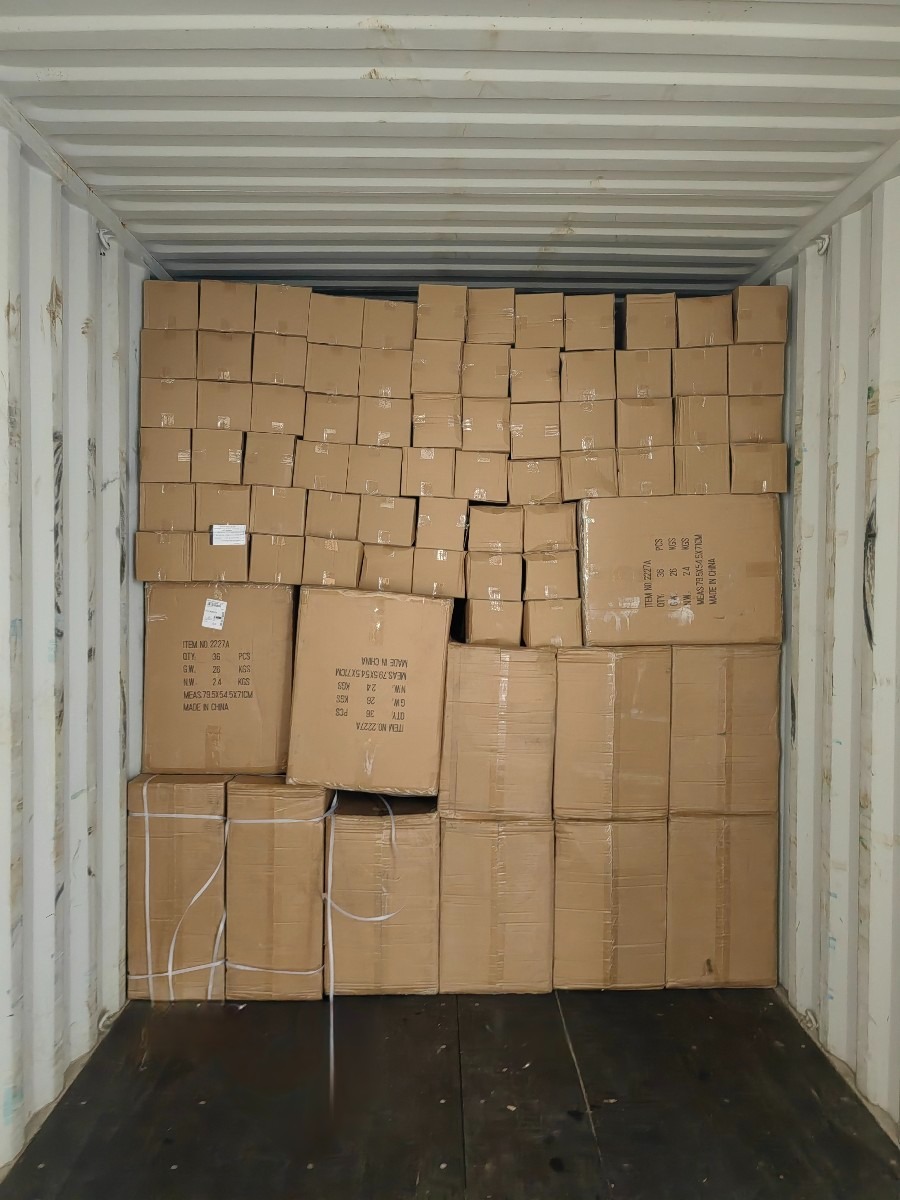 Wnętrze kontenera wypełnione kartonowymi pudłami z widocznymi etykietami informacyjnymi o produkcie.