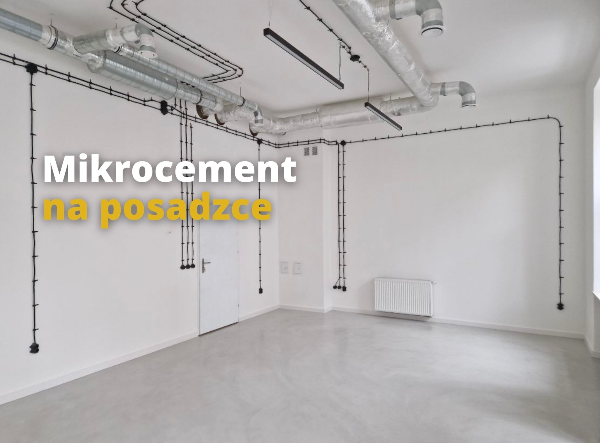 Nowoczesne wnętrze z jasnoszarą, jednolitą posadzką, widoczne czarne kable elektryczne na ścianach, metalowe rury wentylacyjne pod sufitem i minimalistyczne lampy.