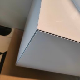 WoodenArt by Dominik Bichta - Fragment białej szafki łazienkowej z umywalką, widoczny z dołu pod kątem, na tle wzorzystej podłogi.