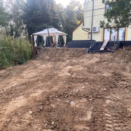 PRZEKOP - Przygotowany teren pod budowę z widocznymi śladami opon, częściowo ułożonymi schodami z bloczków betonowych i altaną w tle.