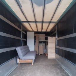 Mateusz Zejer - Wnętrze skrzyni ładunkowej samochodu dostawczego wypełnione meblami: rozkładana sofa, szafki i regały, przygotowane do transportu.