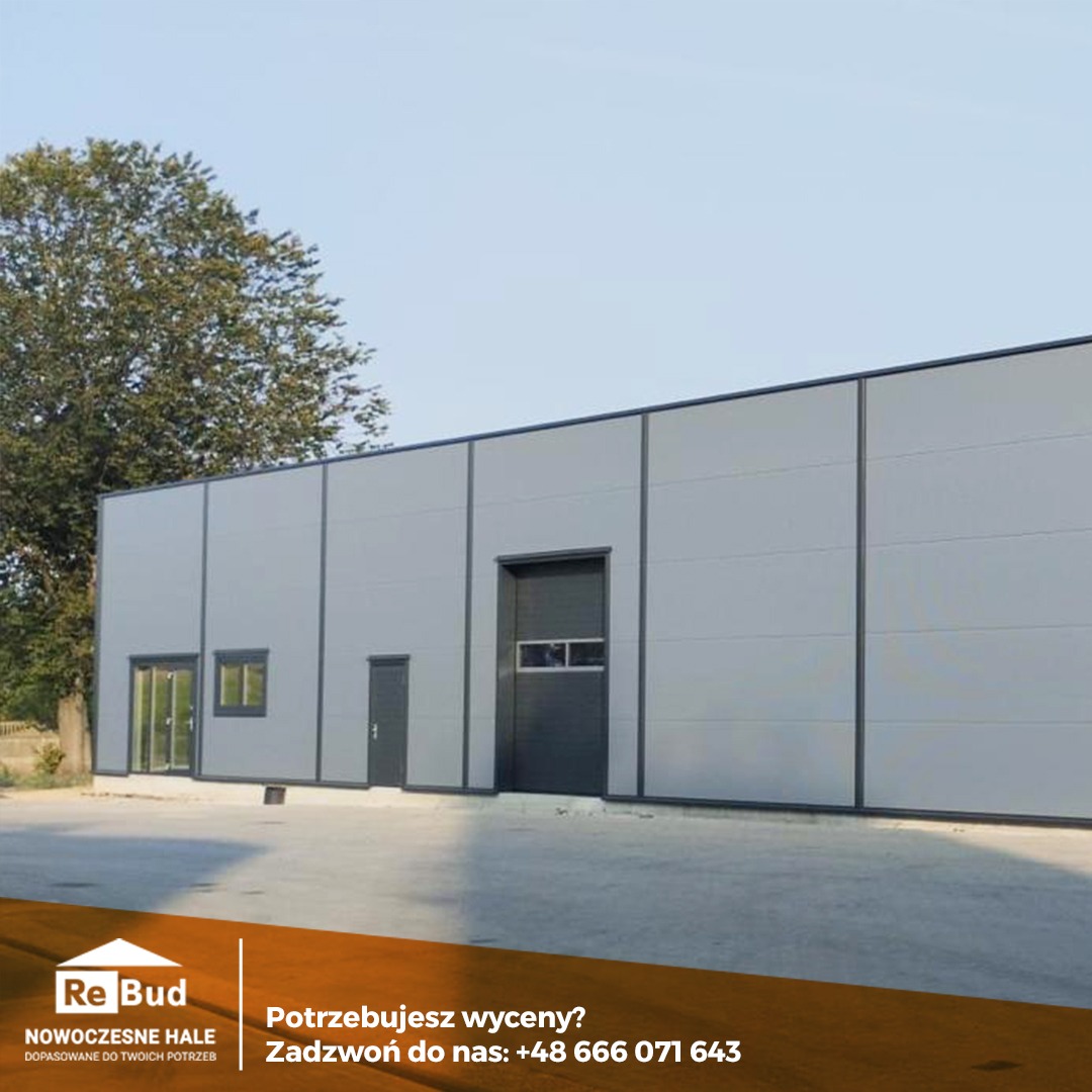 Gotowa hala przemysłowa z płyt warstwowych w Gorzycach Wielkich, widok z zewnątrz, szara elewacja z ciemnymi obramowaniami, brama wjazdowa i drzwi wejściowe.