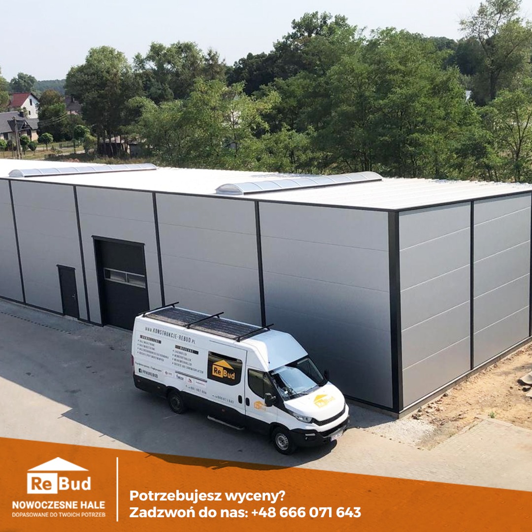 Nowoczesna hala przemysłowa z szarych płyt warstwowych, oświetlona światłem dziennym, z widocznym samochodem dostawczym firmy z logo na boku, zaparkowanym przed budynkiem.