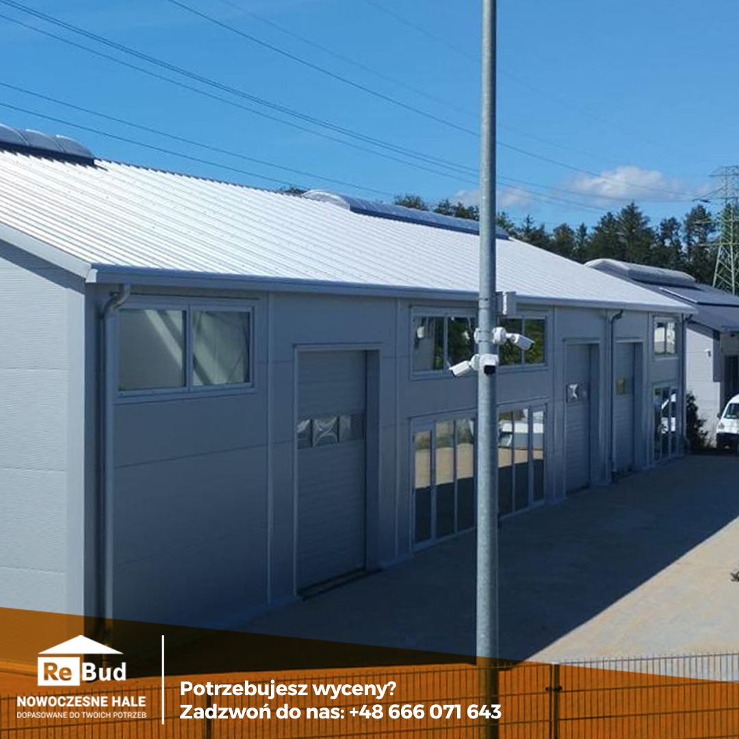 Nowoczesna hala z płyt warstwowych w jasnych kolorach, z widocznymi panelami słonecznymi na dachu i systemem kamer monitoringu zewnętrznego, na tle błękitnego nieba.