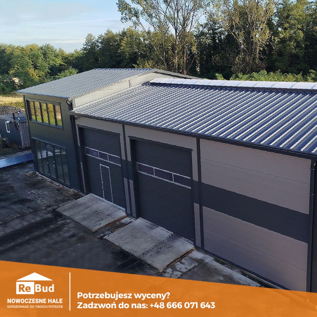 Zrealizowana budowa hali przemysłowej z szarej płyty warstwowej z dwiema bramami segmentowymi i oknami na antresoli, widok z góry na tle zieleni.