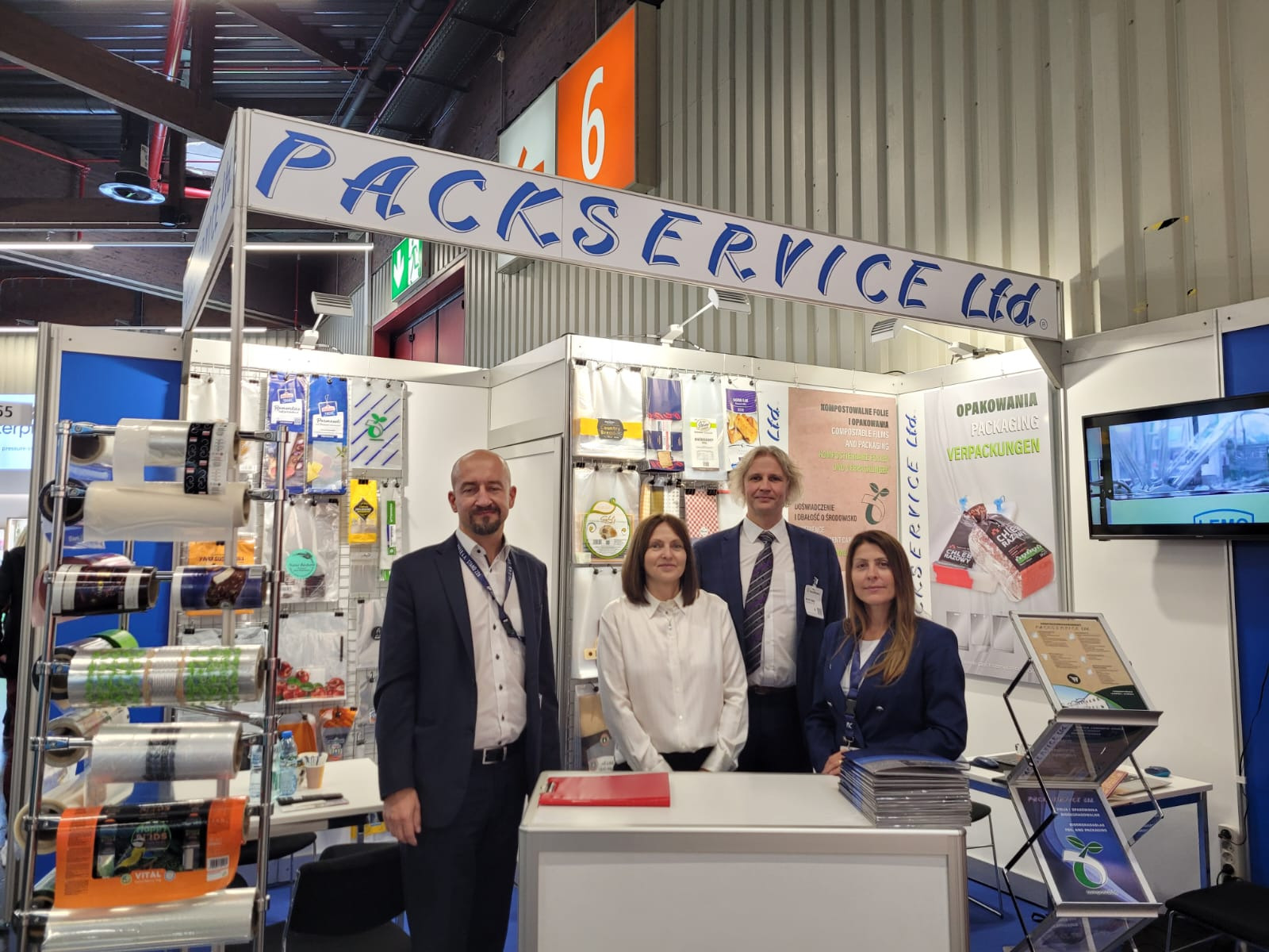 Stoisko firmy Packservice Ltd. na targach opakowań, prezentujące folie kompostowalne i inne materiały do pakowania żywności, z widocznymi pracownikami.