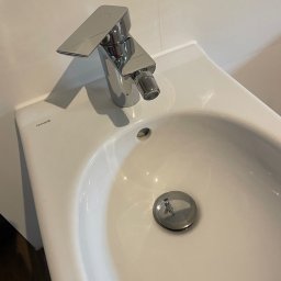 Czysty dom - Biała umywalka Cersanit z chromowaną baterią bidetową o geometrycznym kształcie i widocznym korkiem spustowym.