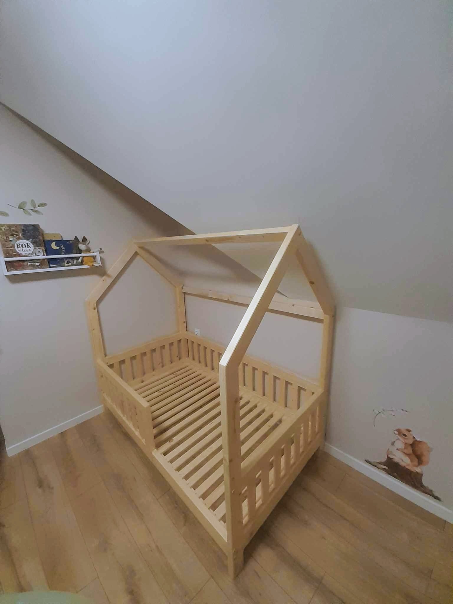 Drewniane łóżko dziecięce w kształcie domku, z drabinką zamiast barierki, ustawione w pokoju na poddaszu w Niedzicy, z naklejką wiewiórek na ścianie i półką na książki w tle.