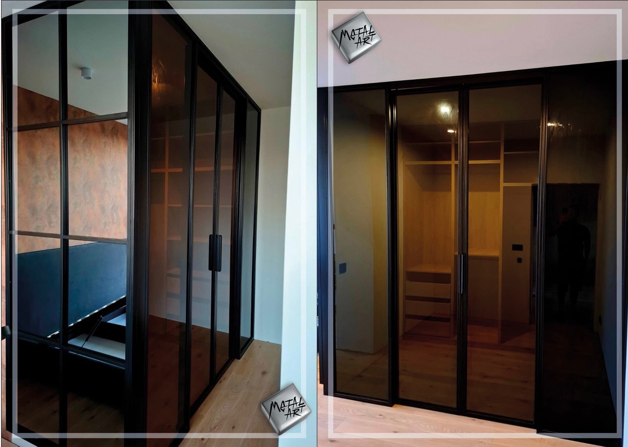 Nowoczesne, przesuwne drzwi metalowe z szybami w kolorze przydymionego brązu, oddzielające garderobę od sypialni, z widoczną strukturą metalowej ramy i minimalistycznymi uchwytami.