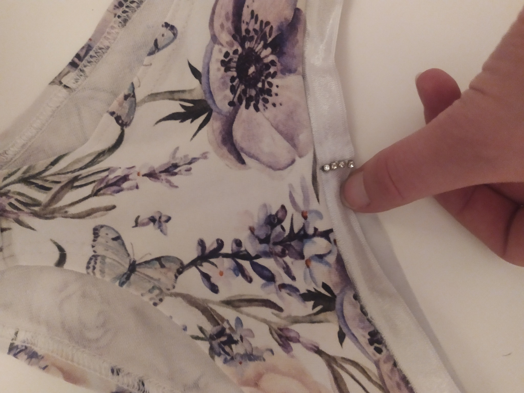 Fragment damskiej bielizny z motywem kwiatowym i motylem, ozdobionej drobnymi kryształkami, prezentowanej w Bydgoszczy.