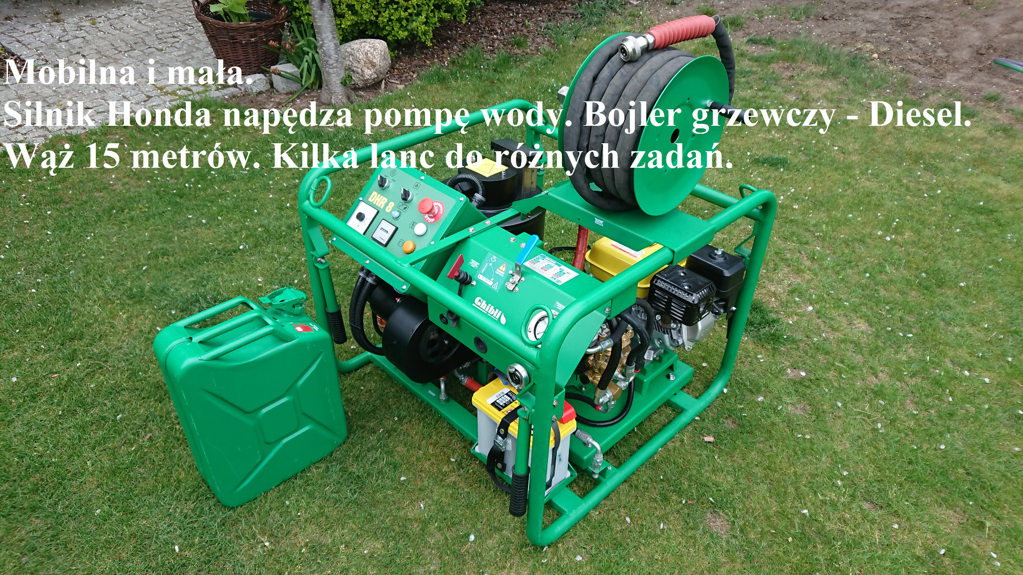 Przenośna, zielona myjka ciśnieniowa z silnikiem Honda i zwiniętym wężem na bębnie, obok kanister na paliwo, ustawiona na trawie.