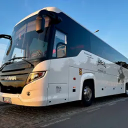 Nowoczesny biało-czarny autokar turystyczny Scania z logo Irex Premium Class, zaparkowany na poboczu drogi, z widoczną tablicą rejestracyjną GDA 1268A