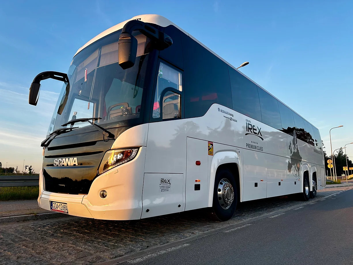 Nowoczesny biało-czarny autokar turystyczny Scania z logo Irex Premium Class, zaparkowany na poboczu drogi, z widoczną tablicą rejestracyjną GDA 1268A