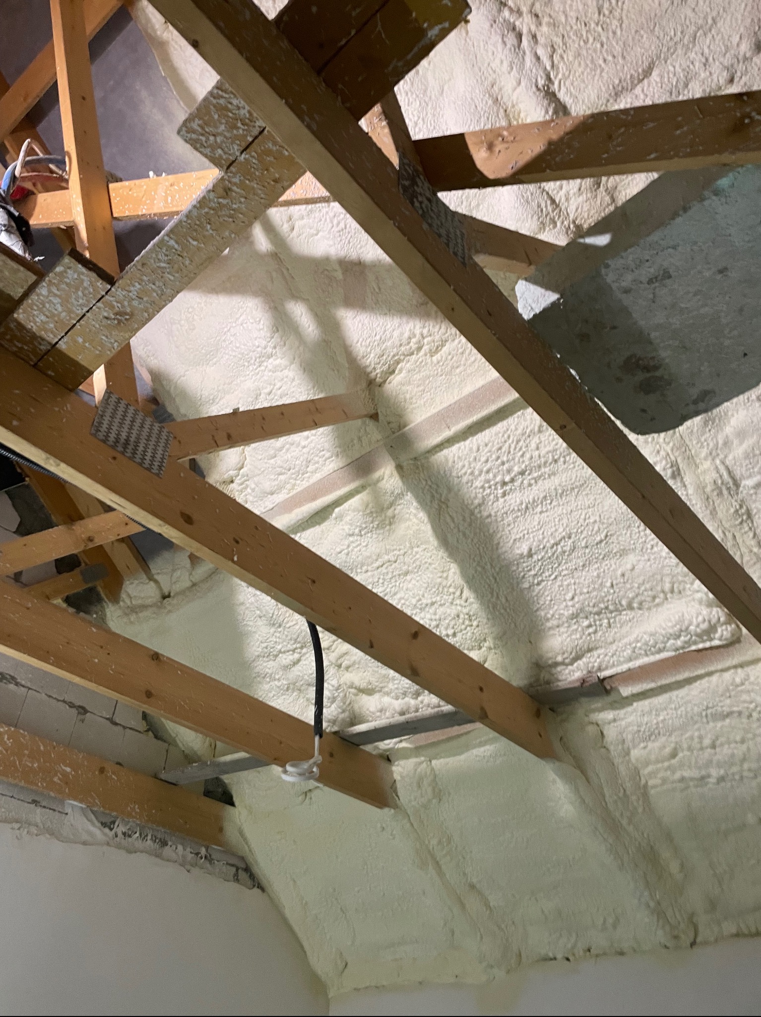 Poddasze w Sławnie po ociepleniu pianką PUR, widoczne drewniane krokwie i biała, gęsta izolacja.