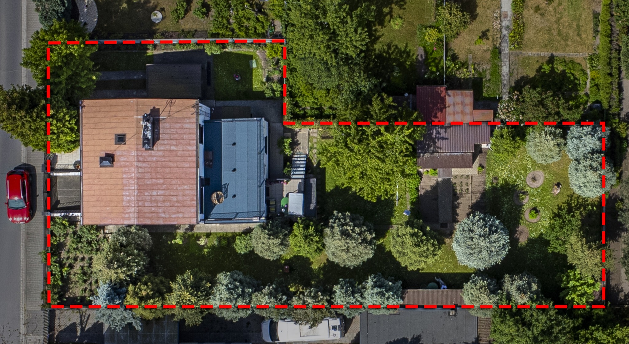 Widok z lotu ptaka na dom z ogrodem, oznaczony czerwoną linią, z widocznym samochodem i vanem zaparkowanymi na ulicy.