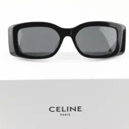 Czarne, masywne okulary przeciwsłoneczne Celine na białym pudełku z logo Celine Paris, widok z przodu, ostre światło.