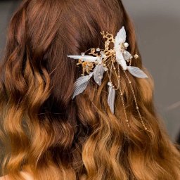 RafalSaduraFotograf.pl - Upięcie ślubne: brązowe włosy z delikatną ozdobą z białych piórek, złotych gałązek i łańcuszków.