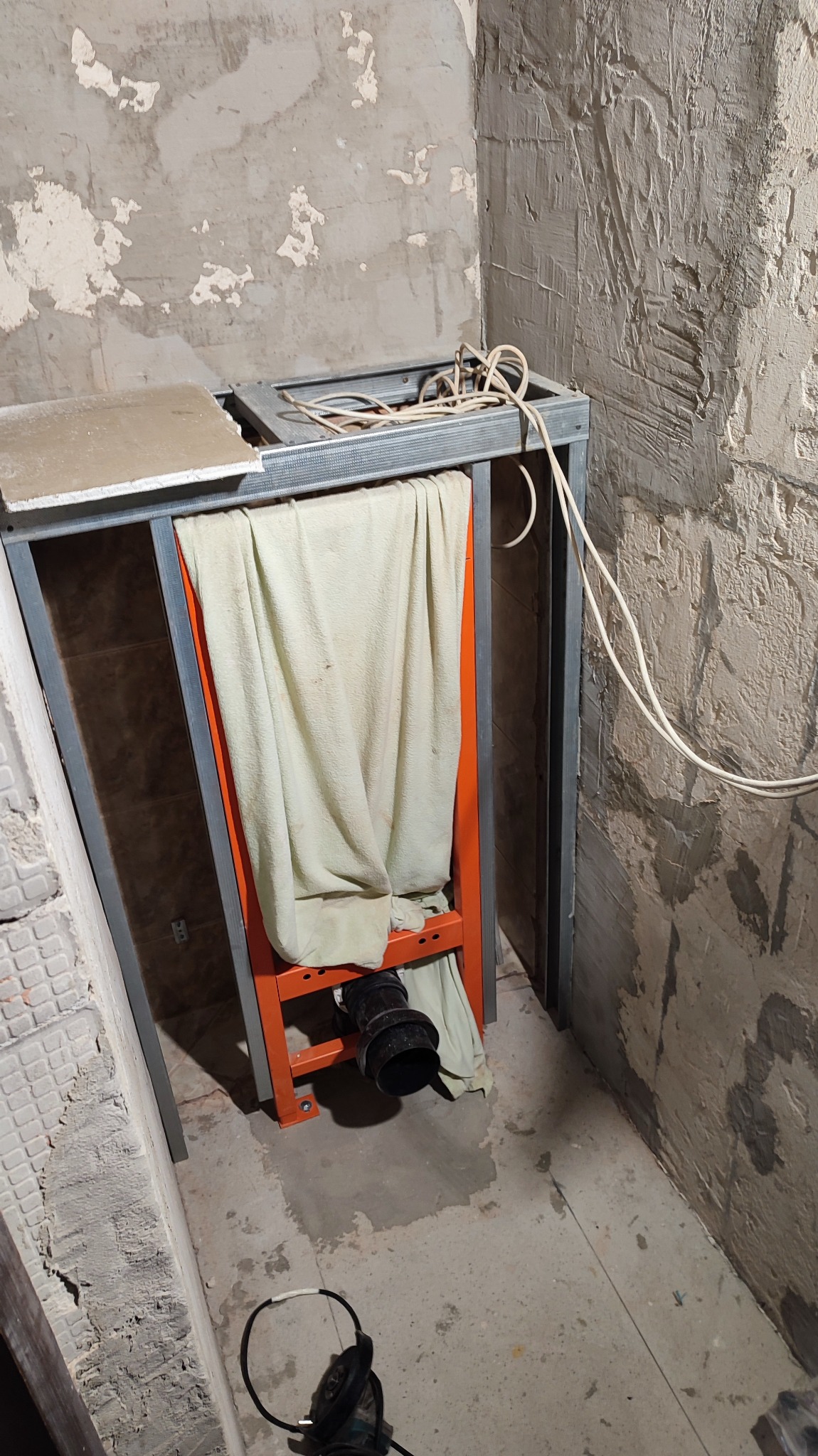 Stelaż podtynkowy WC w trakcie montażu, widoczne elementy instalacji kanalizacyjnej i metalowa konstrukcja, ściany w stanie surowym.