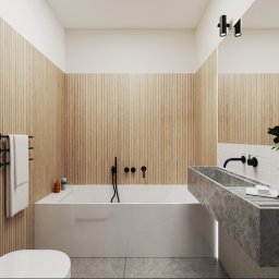 Anna Ostrowska - Nowoczesna łazienka z drewnianymi panelami ściennymi, białą wanną i umywalką z szarego kamienia, akcentowana czarną armaturą i minimalistycznym oświetleniem.