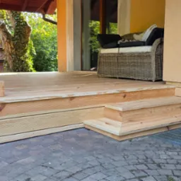 Nowy taras z drewna, z niskimi schodkami, z krzesłem na górze, Kraków. Jasne drewno, widoczne słoje, schludne wykonanie, kostka brukowa dookoła.