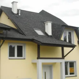 Żółty dom jednorodzinny z czarnym dachem bitumicznym, białymi kominami i oknem dachowym; widoczny fragment elewacji z rynnami i oknem z ogłoszeniem 'A SPRZEDAŻ'.