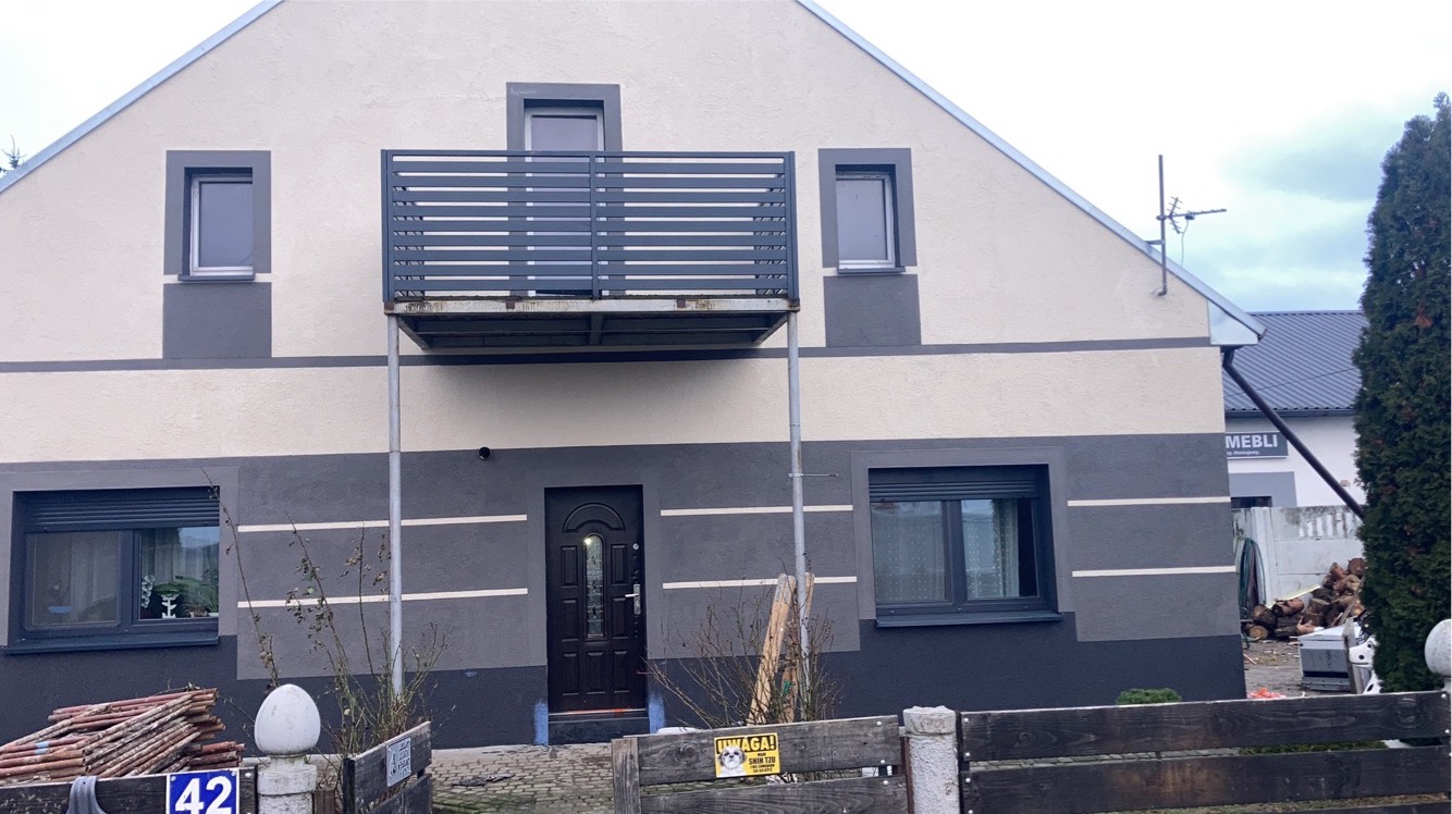 Dwukondygnacyjny dom w Borku Wielkopolskim po remoncie elewacji, z widocznym podziałem kolorystycznym i metalowym balkonem.
