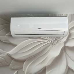 DF HYDRO TRADE SPÓŁKA Z OGRANICZONĄ ODPOWIEDZIALNOŚCIĄ - Biały klimatyzator Kaisai zamontowany na ścianie z dekoracyjną, kwiatową tapetą 3D. Nowoczesny design.