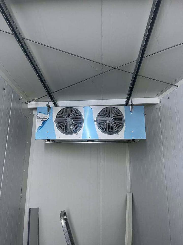 Wnętrze chłodni z zamontowanym agregatem chłodniczym ECO z dwoma wentylatorami. Widoczne metalowe profile i ściany z paneli. Częściowo zdjęta folia ochronna.