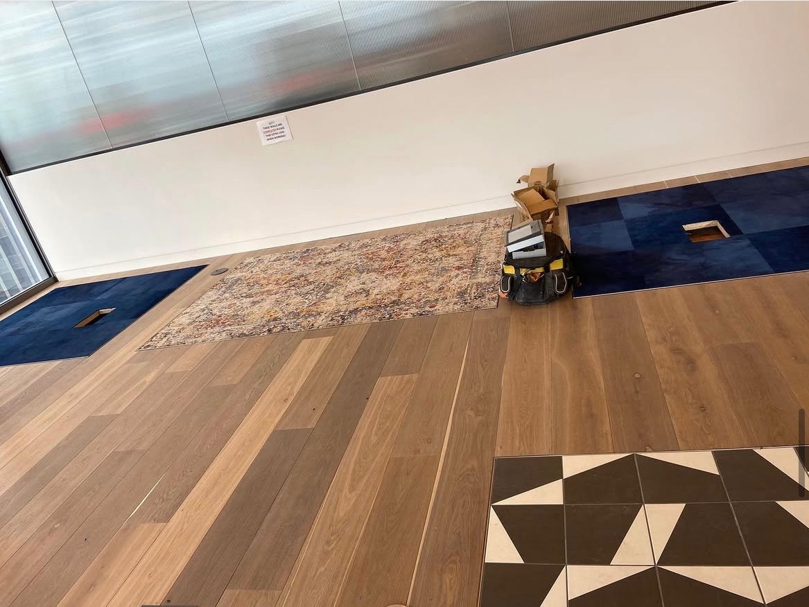 Ułożone panele podłogowe w różnych wzorach i kolorach, widoczny sprzęt i narzędzia pracy. Prezentacja efektu końcowego z bliska, w jasnym oświetleniu.