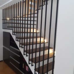 Prestiz Loft - Nowoczesne schody z drewnianymi stopniami i czarną, metalową konstrukcją w Warszawie. Minimalistyczny design z oświetleniem punktowym na każdym stopniu.