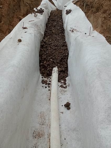 Wykop wyłożony geowłókniną z ułożonym drenażem z rur i kamieni, widok z góry