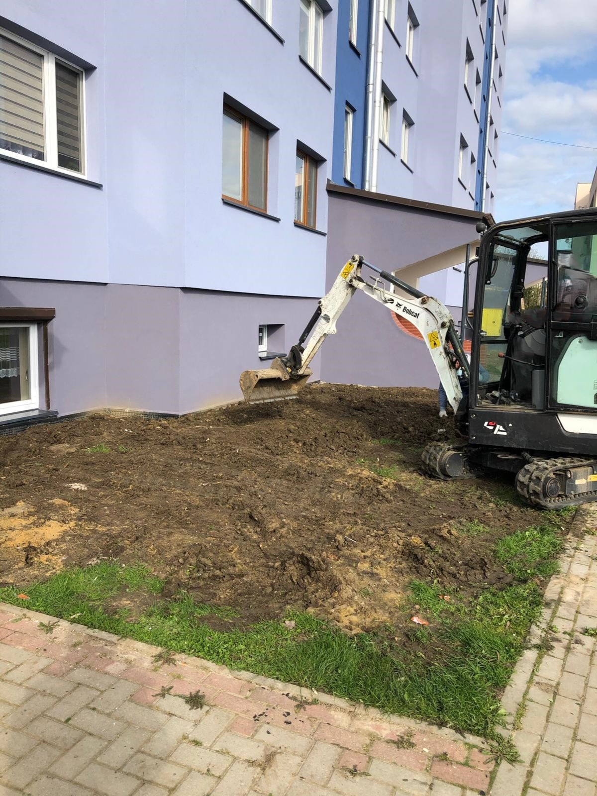 Odkopywanie do fundamentów przy budynku oraz niwelowanie terenu.