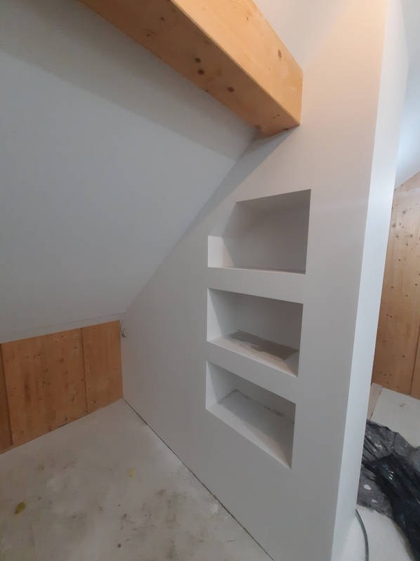 Poddasze w Wałczu w trakcie remontu, z widoczną drewnianą belką stropową i wnękami w ścianie, przygotowanymi do zabudowy.