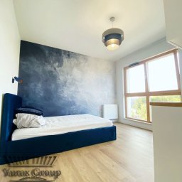 Yury Hancharyk - Sypialnia z łóżkiem w obiciu z granatowego weluru, ściana z efektem malarskim w odcieniach błękitu i szarości, drewniana podłoga i lampa sufitowa z trzema pierścieniami.