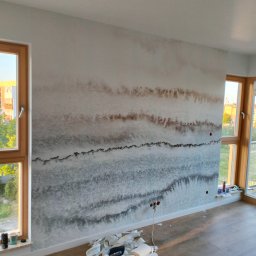 Yury Hancharyk - Ściana w pokoju po malowaniu dekoracyjnym imitującym warstwy geologiczne, widoczne wystające kable, narzędzia pracy i resztki materiałów na podłodze.
