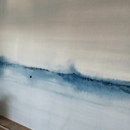 Yury Hancharyk - Ściana z efektem akwareli w odcieniach bieli i niebieskiego, widoczny otwór gniazdka elektrycznego i fragment podłogi z panelami.