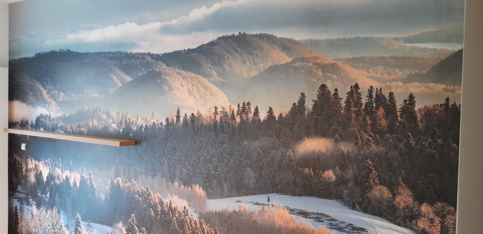 Tapeta z motywem górskiego krajobrazu w zimowej scenerii, z drewnianą półką na pierwszym planie. Realistyczny wzór tapety.