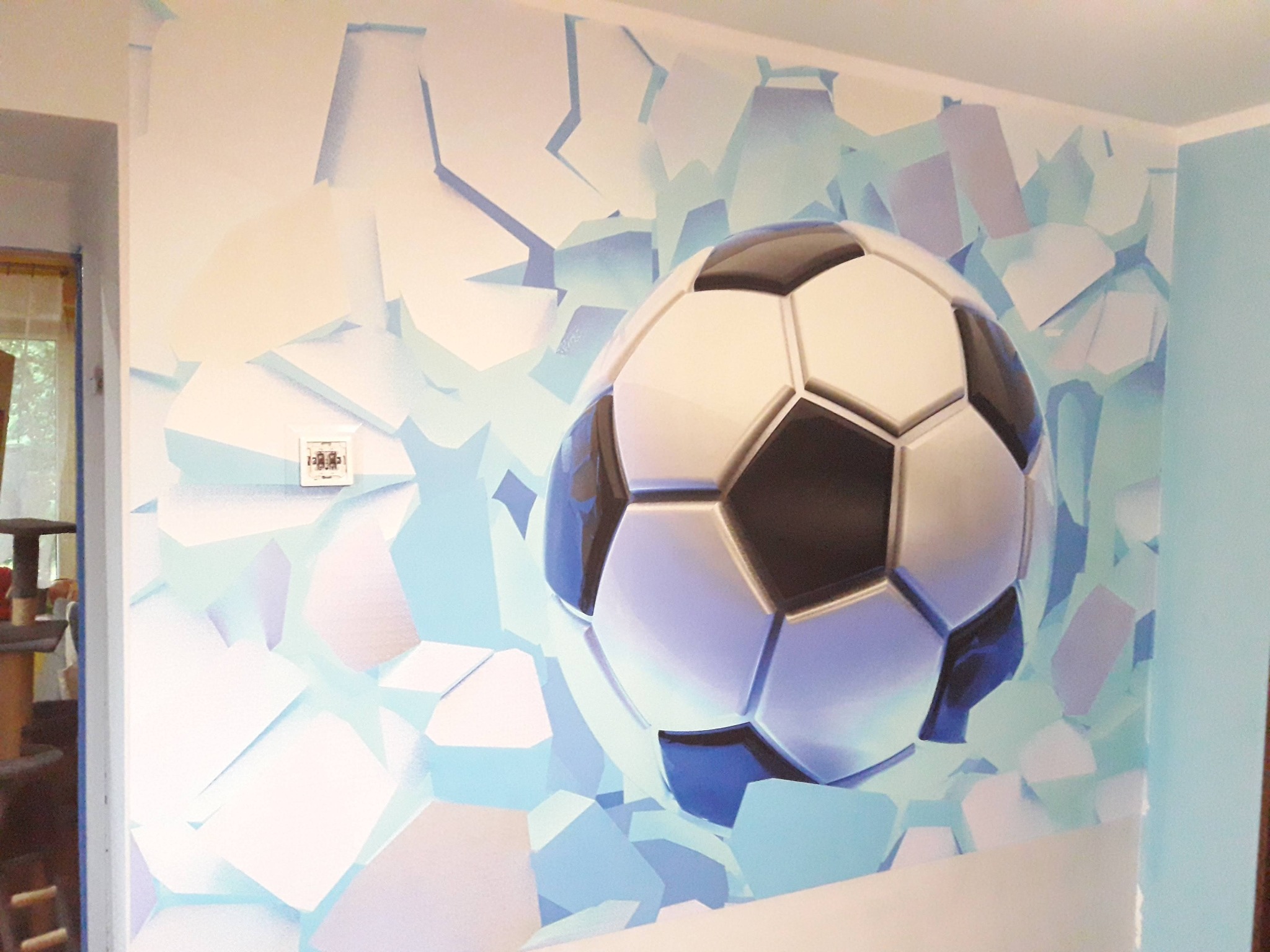 Malowidło ścienne w Mysłowicach: piłka nożna przebija ścianę. Efekt 3D, jasne kolory, nowoczesny design. Dekoracja pokoju dziecięcego.
