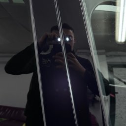 Brand New Car - Błyszczące, czarne słupki okienne w niebieskim samochodzie, odbicie fotografa z lampą błyskową w polerowanej powierzchni.