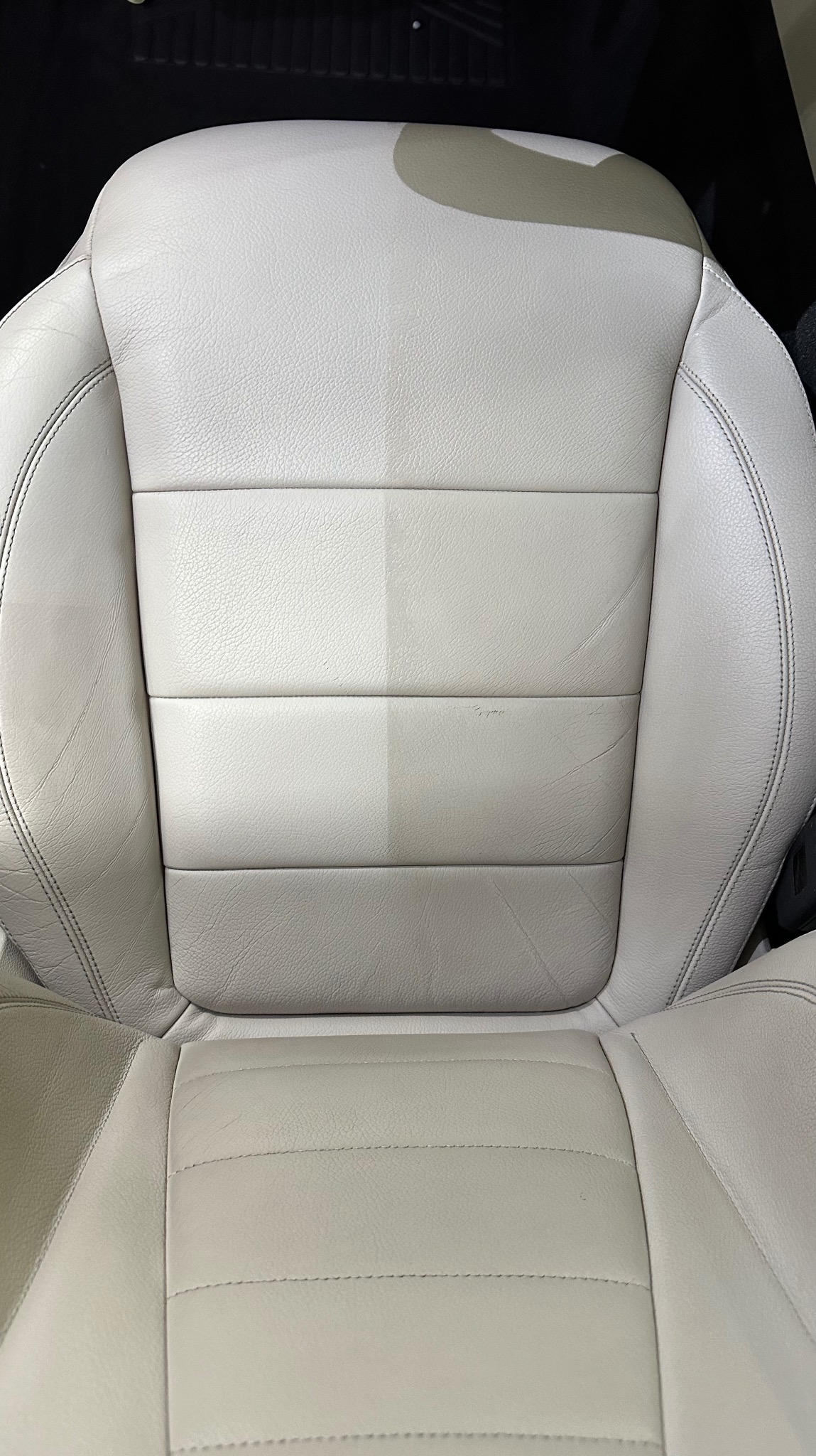 Jasna skórzana tapicerka samochodowa, widoczna różnica w czystości po lewej stronie, ukazująca efekt prania