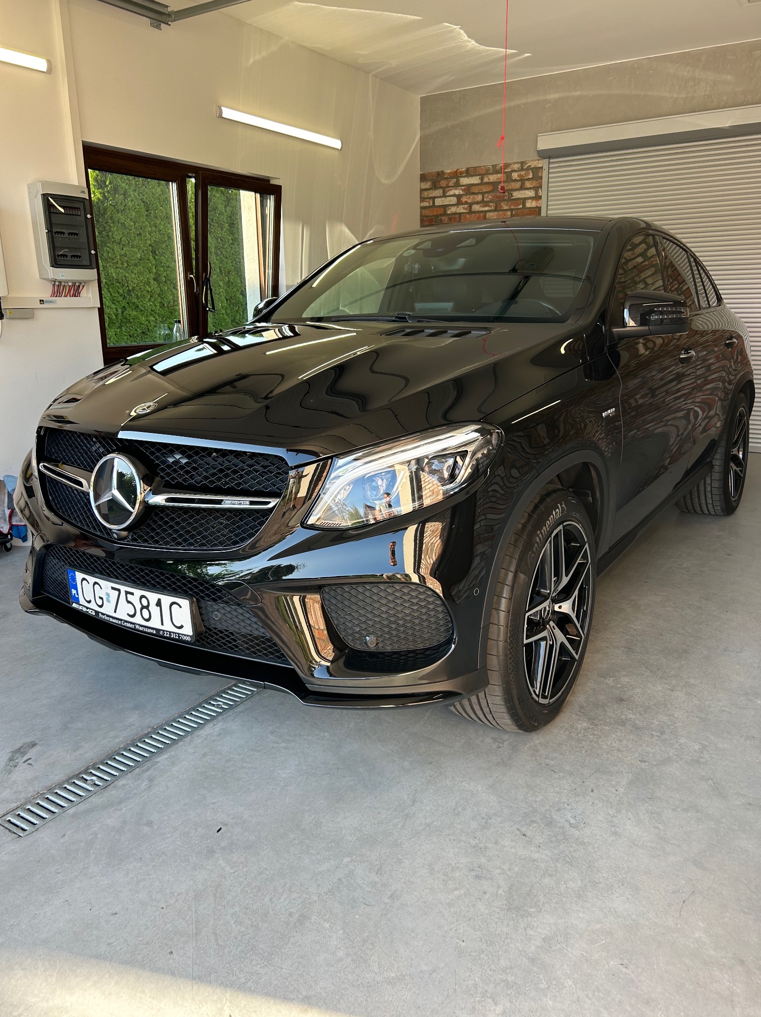 Czarny Mercedes GLE AMG po umyciu, stojący w garażu z kratką odpływową w podłodze.