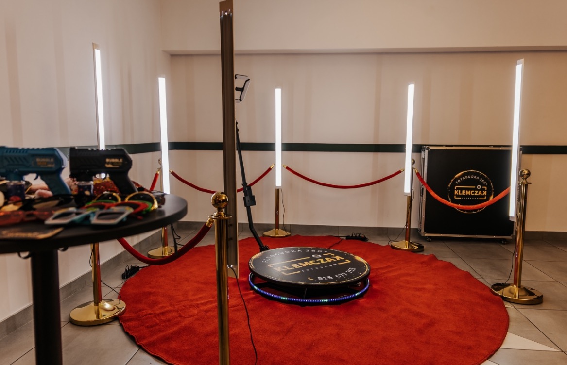 Przygotowane stanowisko z platformą obrotową 360 i rekwizytami w Wieluniu, otoczone czerwonym dywanem i złotymi słupkami z linami, gotowe do robienia pamiątkowych zdjęć.